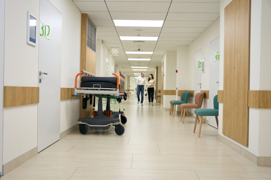 Dark-haired woman and middle-aged man walk along the hospital corridor