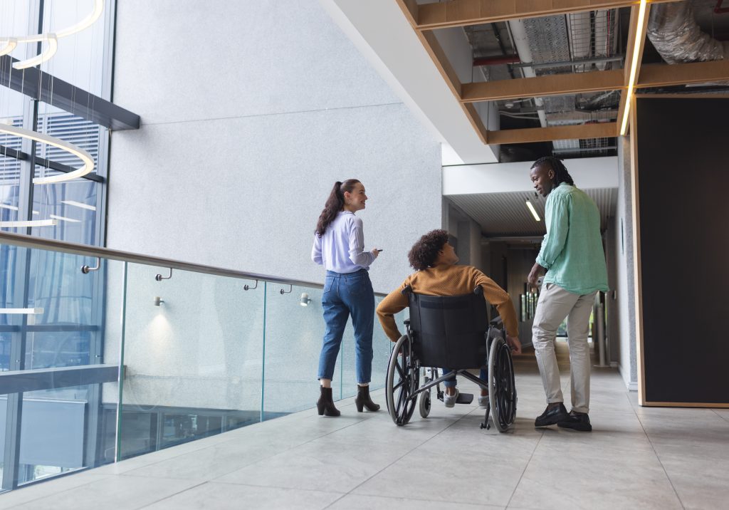 A group of young colleagues chatting in modern hallway in a modern business office, copy space.